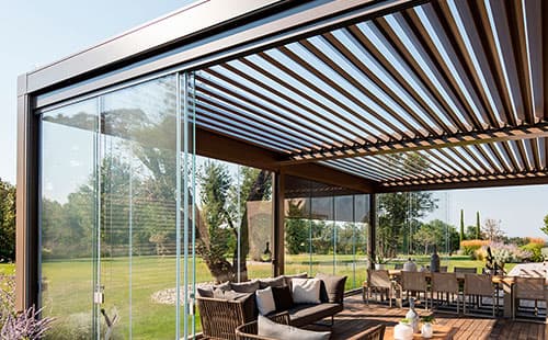 Freistehende Pergola mit Lamellendach und schiebbaren Glaswänden